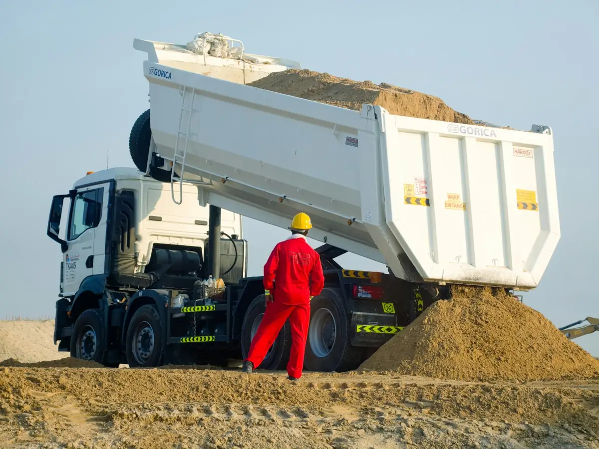 Camion benne déchargeant du sable sur une plateforme